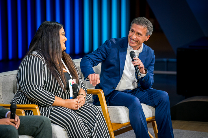 Two panelists sit on stage smiling and talking during a discussion.