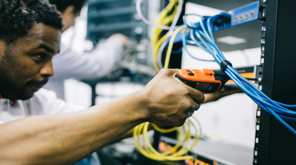 Technician using a cable tester on network cables in a server rack.