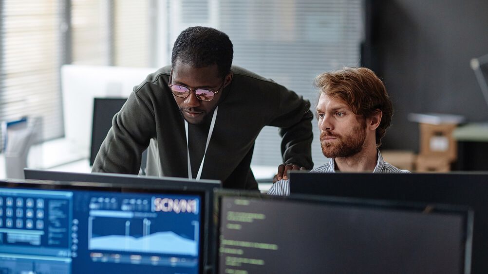 Coding engineers in workspace looking at computer