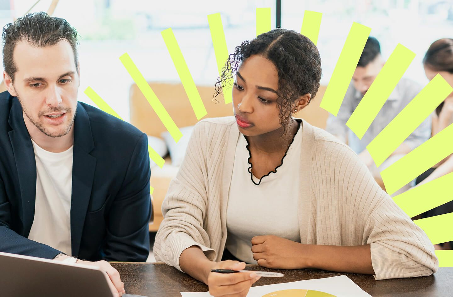 Two coworkers review documents at a meeting table, surrounded by bright yellow graphic rays, creating an energetic, collaborative mood.