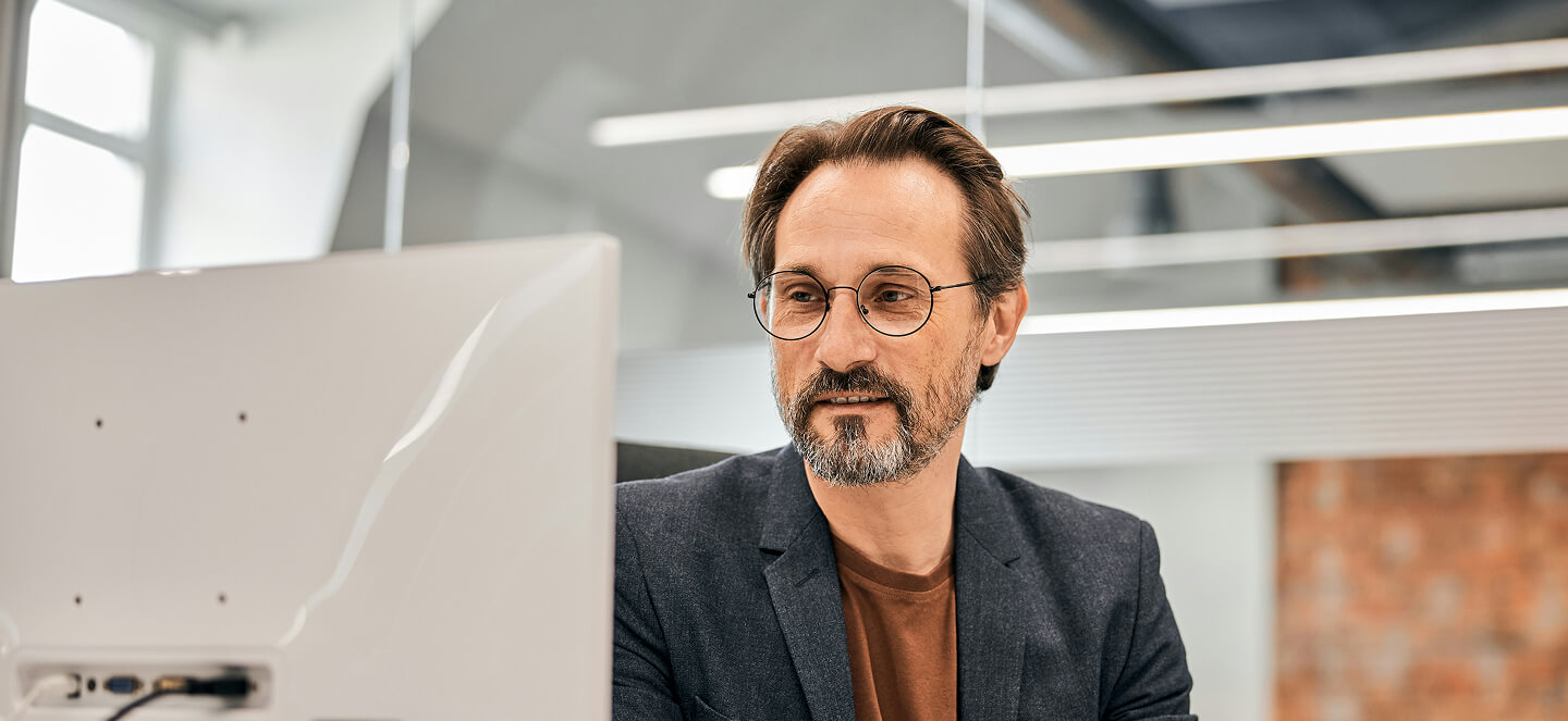Focused and professional man at a desk looking at a computer monitor.