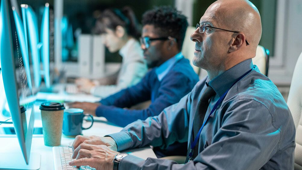 Group of employees seated at desk working on computers