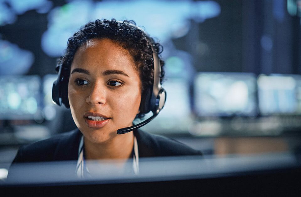 Woman IT support with headset working on computer