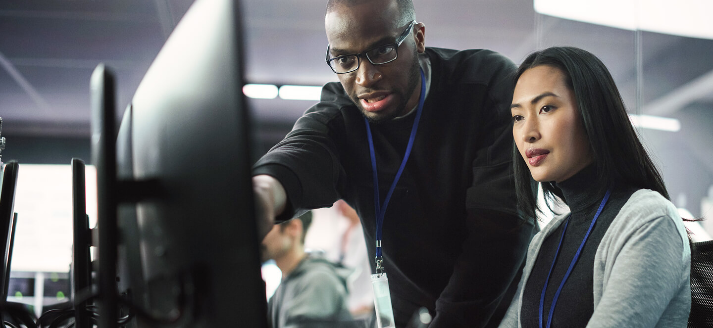 Mentor helping coding student on computer