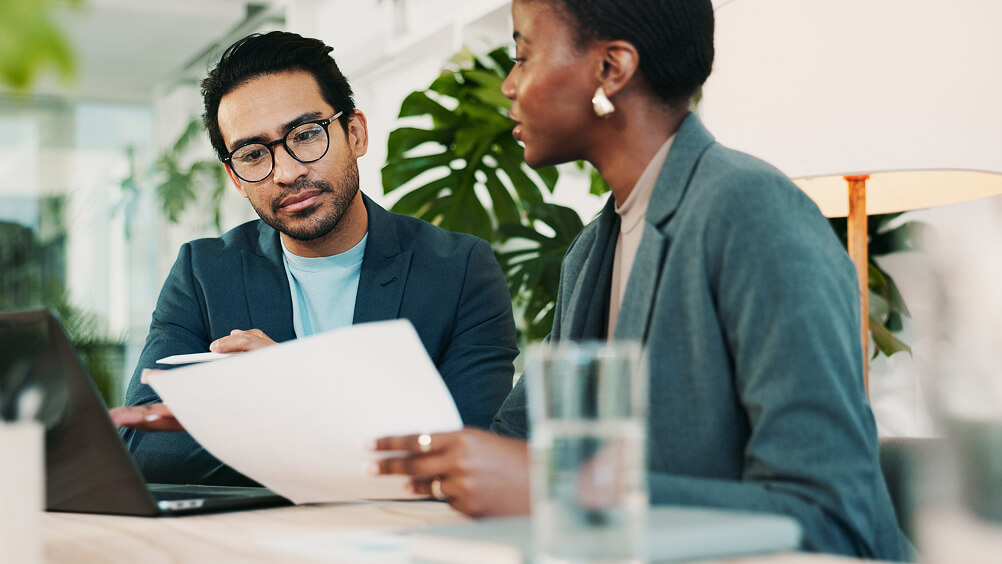 Employees in conversation at desk workspace
