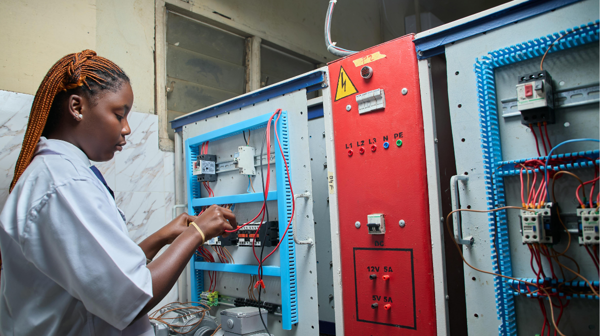 Female technician working on wiring inside electrical control panels.