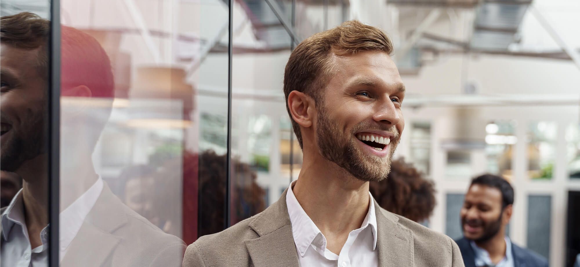Businessman standing in office and looking at side on colleagues background