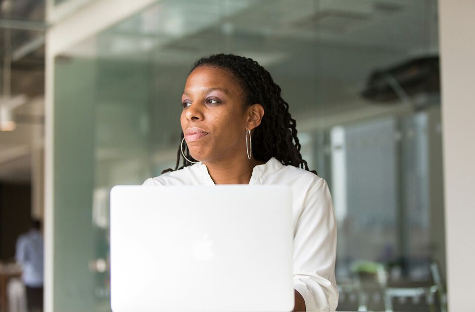 Professional women sitting in front of laptop in office environment.