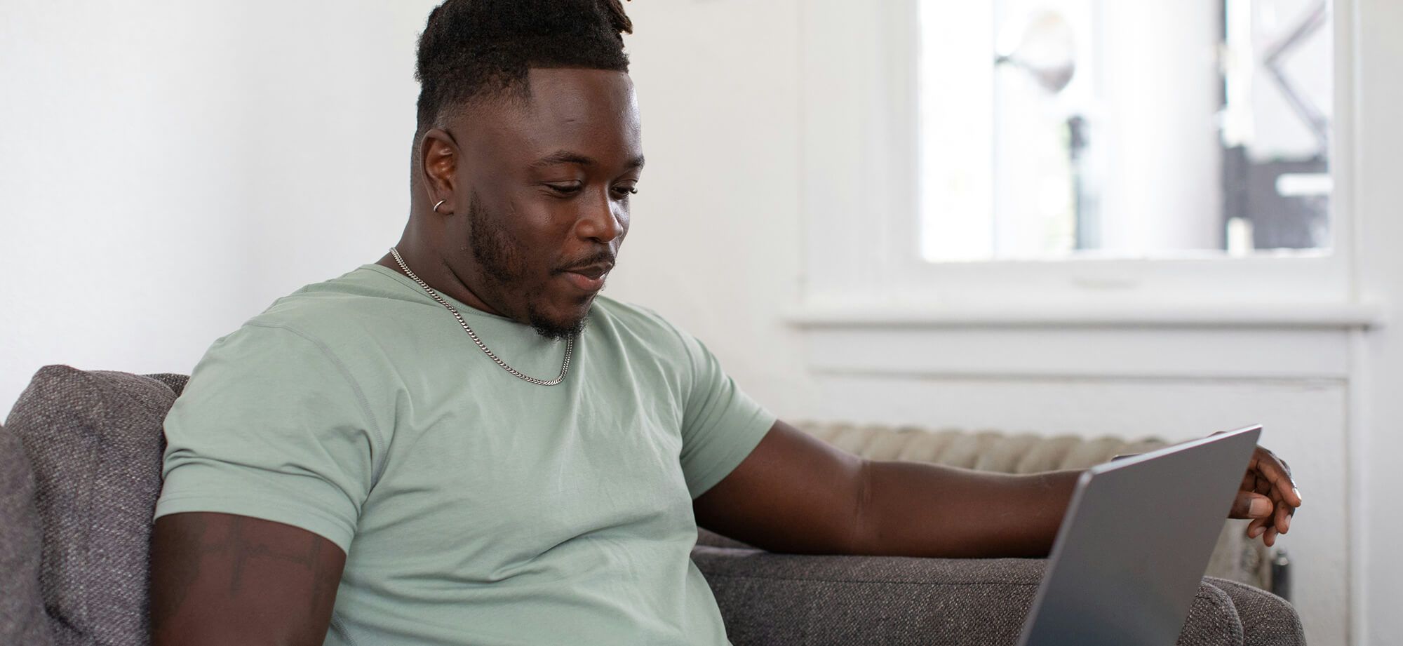 Man seated on couch looking at laptop