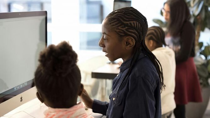 Students in classroom collaborating in front of computer screen.