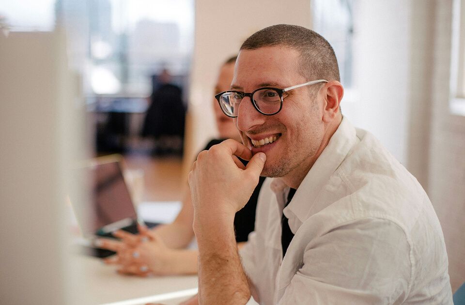 Male professional smiling while working on a computer.