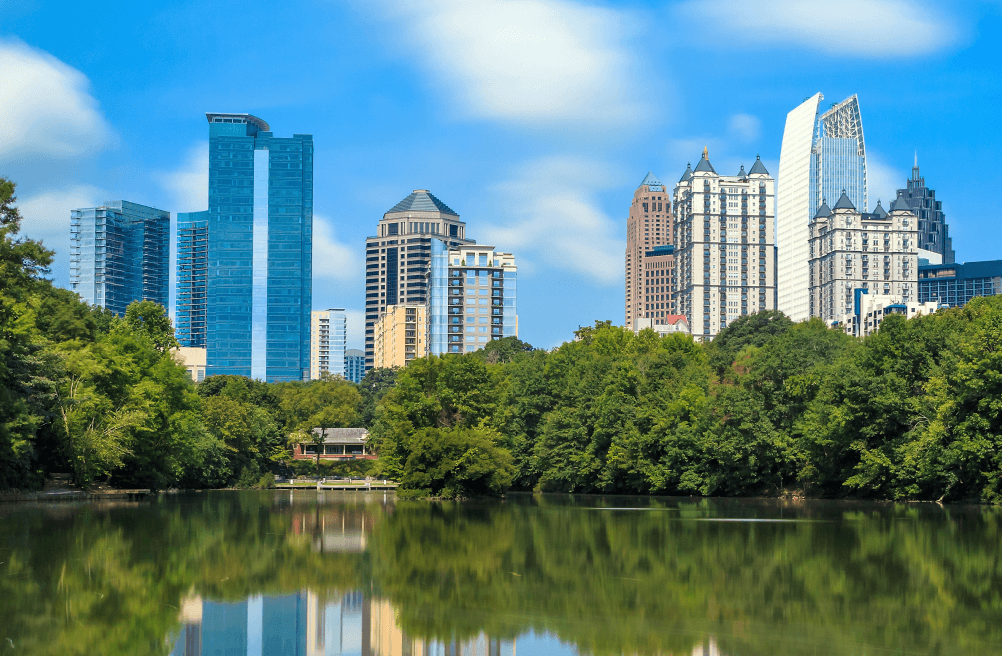 Atlanta skyline rising above lush trees and a reflective lake.