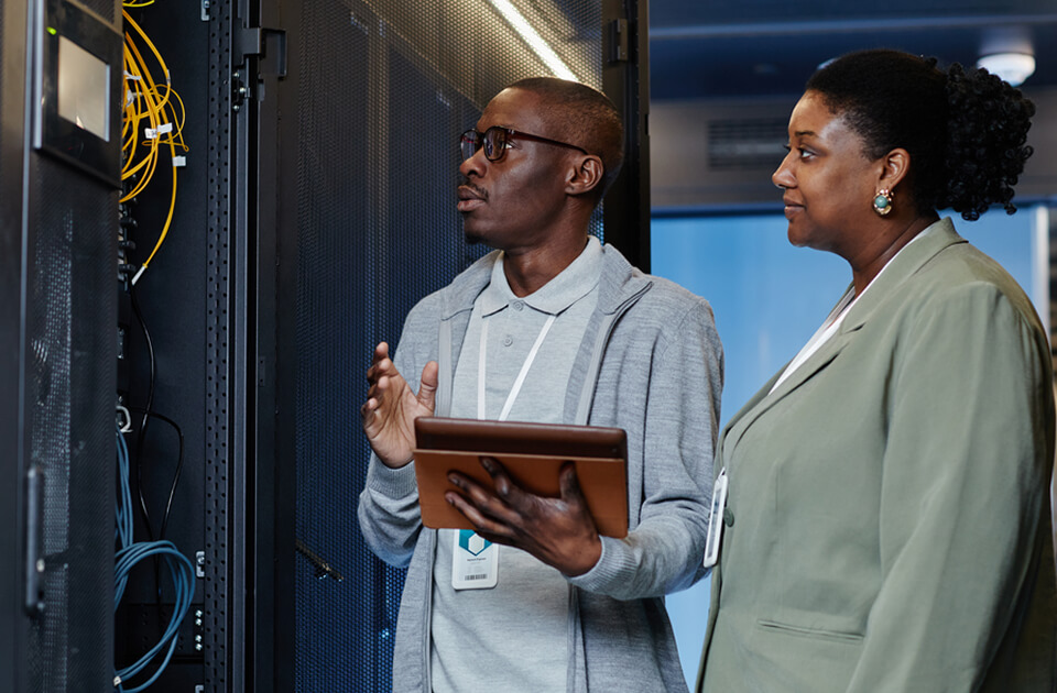two people inspecting a server cabinet