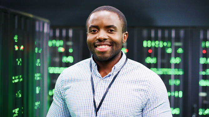 Smiling man standing in a server room.