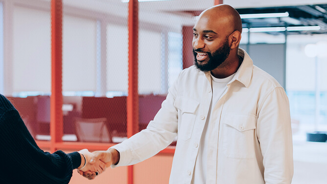 Two adults shaking hands in a professional office setting.