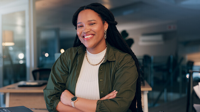 Smiling adult female learner seated in a modern classroom or office.