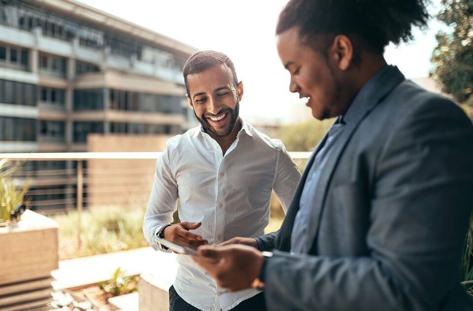 Two male professionals having a conversation outside on building balcony. 