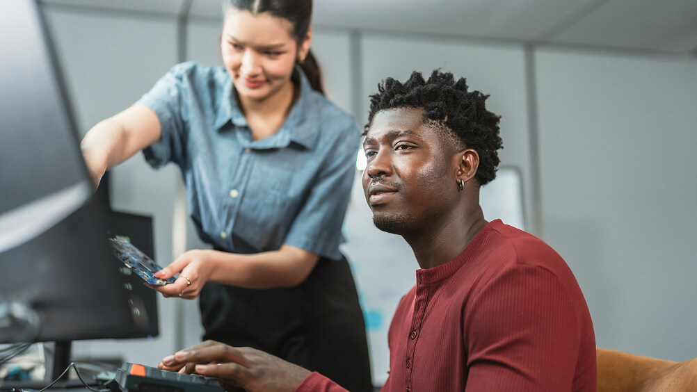 Mentor training new hire on computer in workspace setting