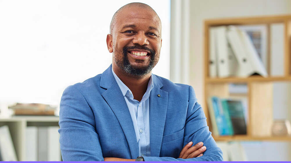 Employee in workspace with arms folded smiling